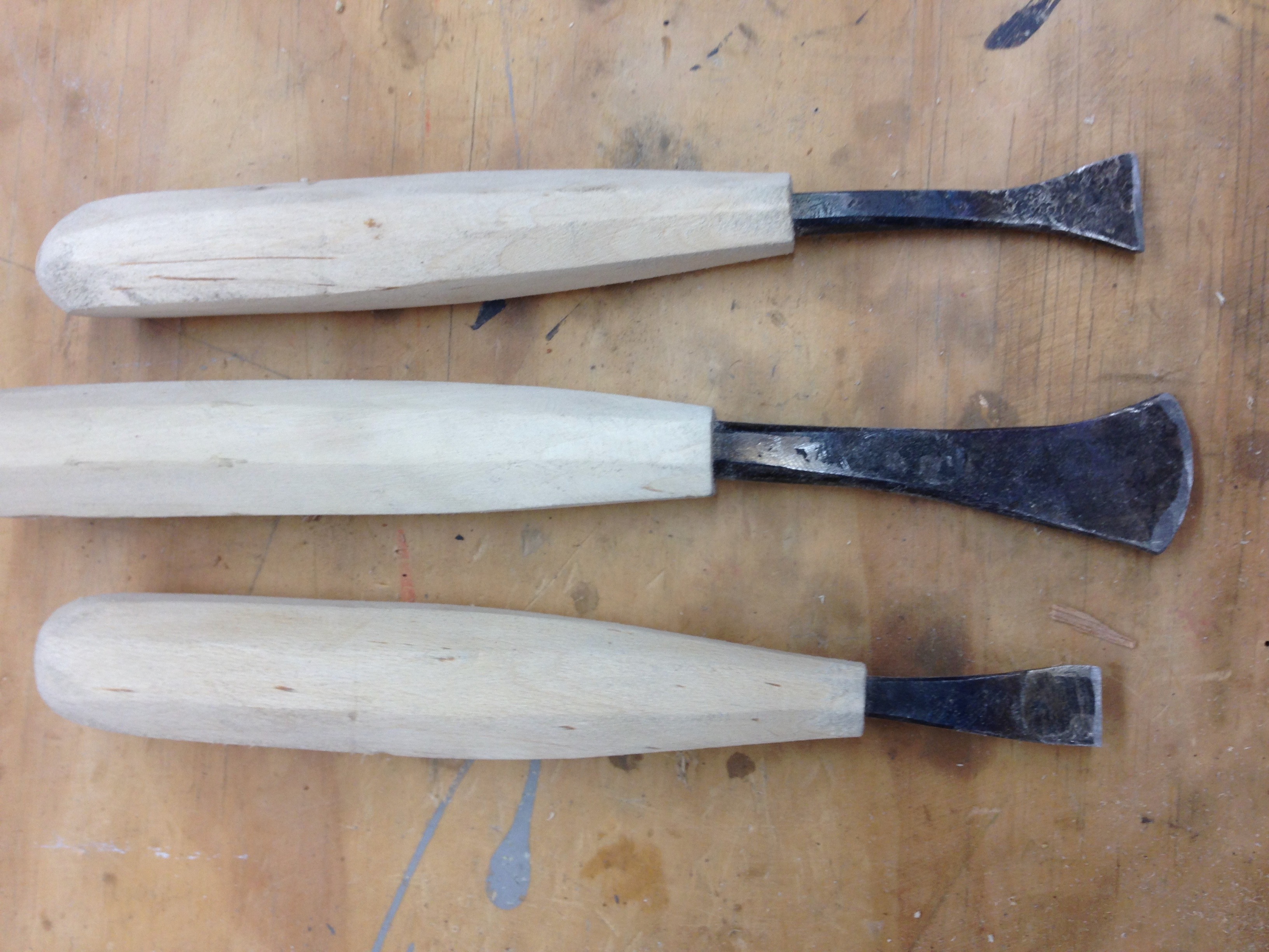 Students forging wood carving tools at the anvil