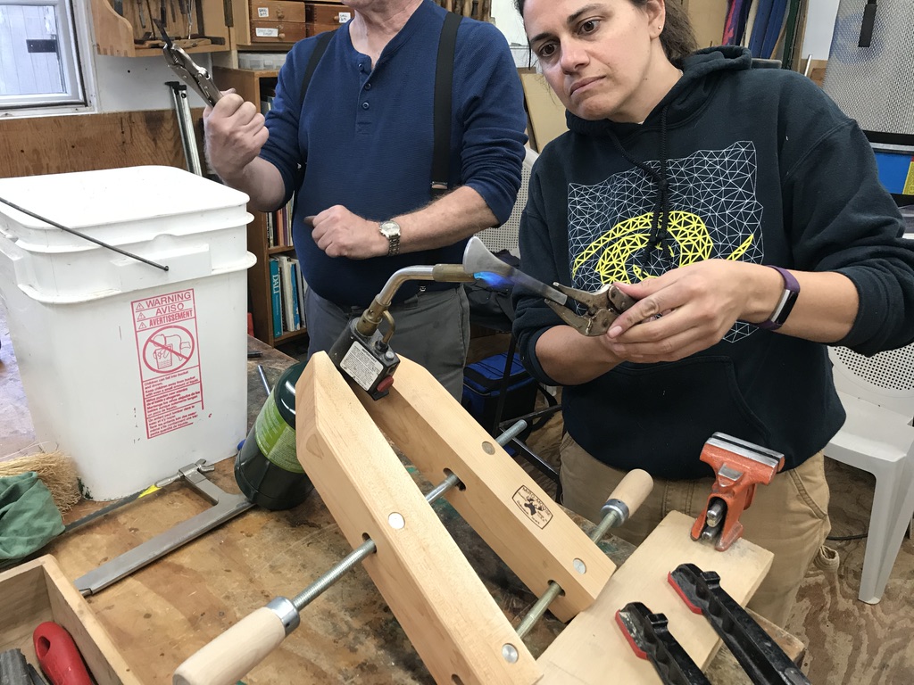 Students fitting a handle with a torch and clamps